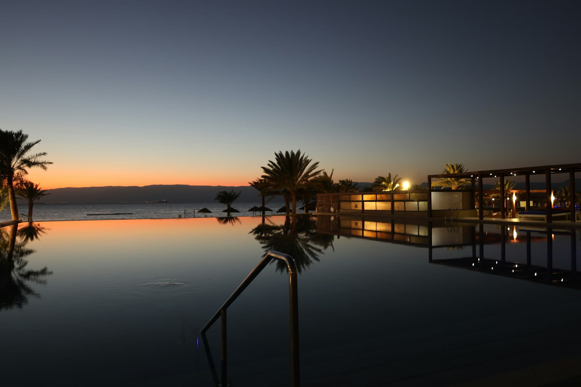 Infinity pool at dusk, palms above the sea